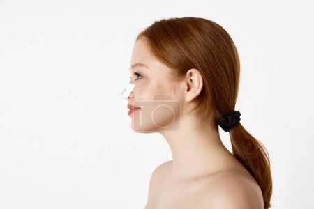 Photo for Side view portrait of beautiful young girl with a bandage on her nose after rhinoplasty over white studio background. Perfect shape. Beauty, plastic surgery, rhinoplasty, cosmetology, health concept - Royalty Free Image