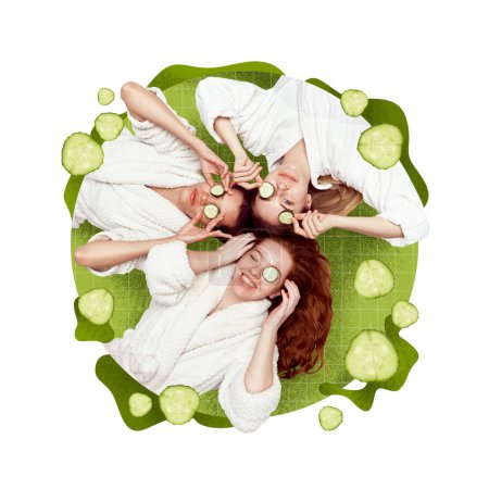 Foto de Tres hermosas chicas jóvenes en albornoz haciendo máscara con pepino. Cuidado de los rayos y vitaminas. Diseño conceptual creativo. Concepto de cosmetología, belleza femenina, cuidado de la piel, salud, cosméticos - Imagen libre de derechos