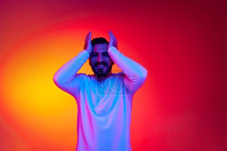 Photo for Portrait of handsome bearded man smiling, posing with positive mood against gradient studio background in neon light. Surprise. Concept of human emotions, facial expression, lifestyle - Royalty Free Image