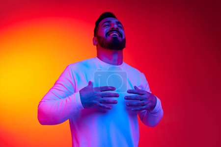Photo for Portrait of handsome bearded man smiling, laughing, posing with positive mood against gradient studio background in neon light. Concept of human emotions, facial expression, lifestyle - Royalty Free Image