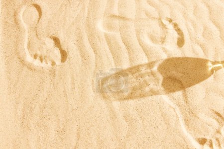 Foto de Sombra de vaso de cerveza sobre arena tibia. Imagen texturizada. Chile de playa en el cálido día de verano con bebida fresca, refresco y relajación. Concepto de bebida alcohólica, sabor, vacaciones de verano, vacaciones, cervecería. Anuncio - Imagen libre de derechos