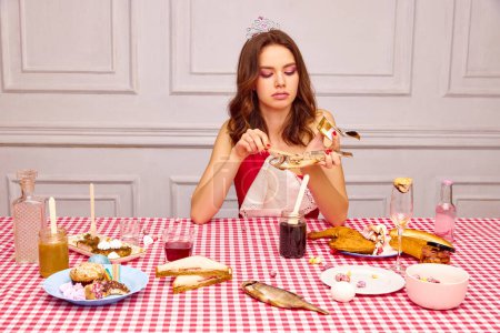 Foto de Retrato de una hermosa joven sentada en la mesa, celebrando su cumpleaños, comiendo pescado. Aperitivos extraordinarios. Concepto de fiesta, celebración, emociones, belleza femenina, juventud. Arte pop - Imagen libre de derechos