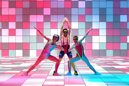 Serious, funny men in colorful sportswear training, having fun against multicolored mosaic studio background in neon light. Concept of sportive and active lifestyle, humor, retro style. Ad