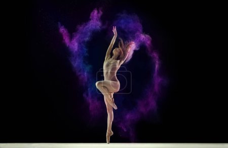 Téléchargez les photos : Jeune fille tendre, danseuse de ballet en body beige dansant avec de la poudre colorée sur fond studio noir. Concept d'art, festival, beauté de la danse, inspiration, jeunesse, grâce - en image libre de droit