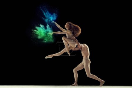 Téléchargez les photos : Jeune homme et femme artistique, danseurs de ballet talentueux en body beige dansant avec explosion de poudre colorée sur fond noir. Concept d'art, festival, beauté de la danse, inspiration, jeunesse - en image libre de droit