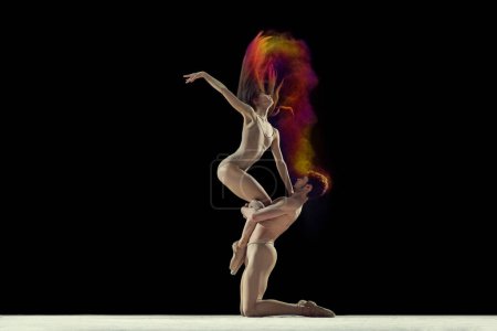 Photo for Expressive dance. Young man and woman, ballet dancers making performance with powder explosion against black studio background. Concept of art, festival, beauty of dance, inspiration, youth - Royalty Free Image