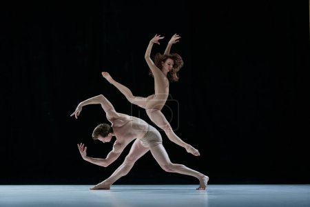 Graceful, artistic couple, man and woman, professional ballet dancers performing against black studio background. Concept of beauty, classical dance style, inspiration, movements. Ad