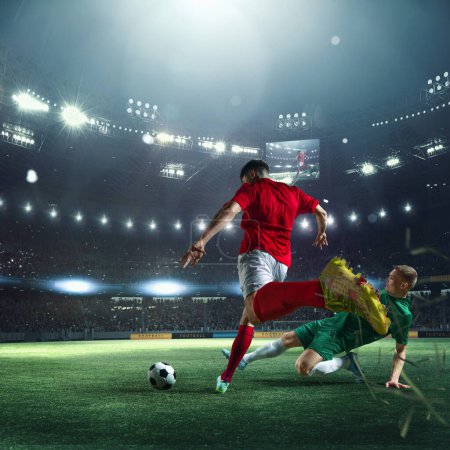 Photo for Live match. Football players in uniform during game, playing at 3D stadium with flashlights and blurred audience on background. Concept of professional sport, championship, game, achievement - Royalty Free Image