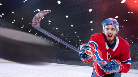 Foto de Joven competitivo, motivado, jugador de hockey profesional en uniforme con palo de pie en la pista de hielo 3D arena con linternas. Concepto de deporte, competición, partido, juego, acción y movimiento - Imagen libre de derechos