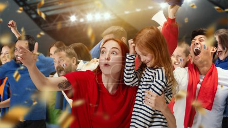 Photo for Young woman, sport fan showing little girl her favourite football team. People, football fans attending match to watch game and cheer up team. Sport, leisure time, emotions, hobby and entertainment - Royalty Free Image