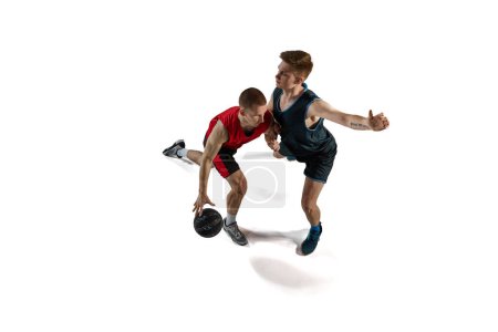 Téléchargez les photos : Deux joueurs de basket professionnels en mouvement, jouant avec le ballon, s'entraînant isolés sur fond blanc. Concept de sport, action et mouvement, santé, jeu, passe-temps, vêtements de sport, publicité - en image libre de droit