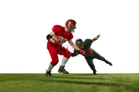 Téléchargez les photos : Image dynamique de deux hommes en uniforme footballeurs américains en mouvement sur le terrain pendant le jeu tendu sur fond blanc. Concept de sport professionnel, action, mode de vie, compétition, entraînement, publicité - en image libre de droit