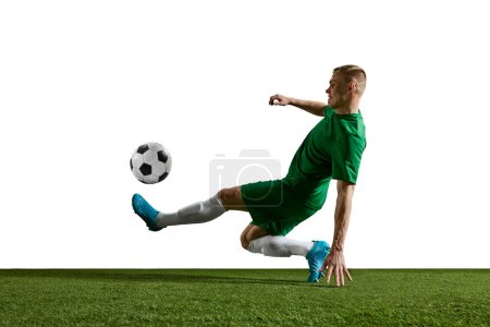 Photo for Young motivated man, football player in green uniform in motion, training, playing against white background. Concept of professional sport, action, lifestyle, competition, hobby, training, ad - Royalty Free Image