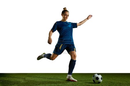 Photo for Young sportive girl in blue uniform, football player in motion, training, kicking ball against white background. Concept of professional sport, action, lifestyle, competition, hobby, training, ad - Royalty Free Image