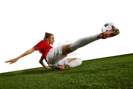 Photo for Motivated female athlete, young girl, football player kicking ball in motion on field grass against white background. Concept of professional sport, action, lifestyle, competition, hobby, training, ad - Royalty Free Image