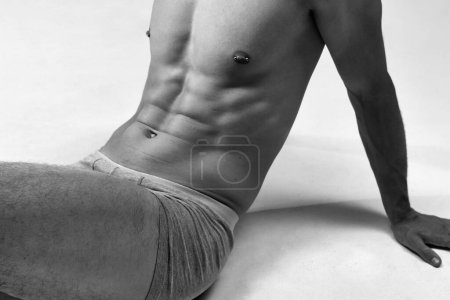 Photo for Black and white cropped image of male muscular, relief, fit, strong body. Model posing on floor in underwear. Concept of male natural beauty, body care, health, sport, fashion, ad, art - Royalty Free Image