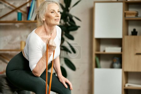 Téléchargez les photos : Entraînement actif, positif et pour les femmes âgées à la maison dans le salon, faisant de l'exercice avec un équipement de fitness pour les mains. Concept de style de vie sportif et sain, âge, soins du corps, fitness, bien-être. - en image libre de droit