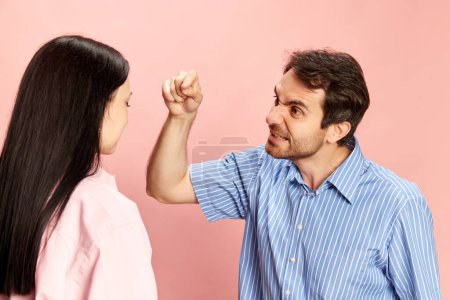 Photo for Man emotionally talking to woman, expressing anger, disagreement and irritation against pink studio background. Concept of friendship, relationship, communication, emotions, lifestyle, ad - Royalty Free Image