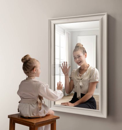 Téléchargez les photos : Collage conceptuel créatif. Petite fille regardant dans le miroir et voyant le reflet de la jeune fille. Saluant son futur moi. Concept de présent, passé et futur, âge, mode de vie, génération, annonce - en image libre de droit