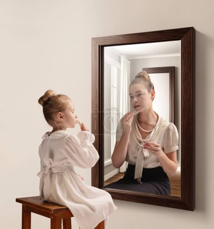 Photo for Creative conceptual collage. Little girl looking in mirror and seeing reflection of young girl, her future self. Aging. Concept of present, past and future, age, lifestyle, memories, generation, ad - Royalty Free Image