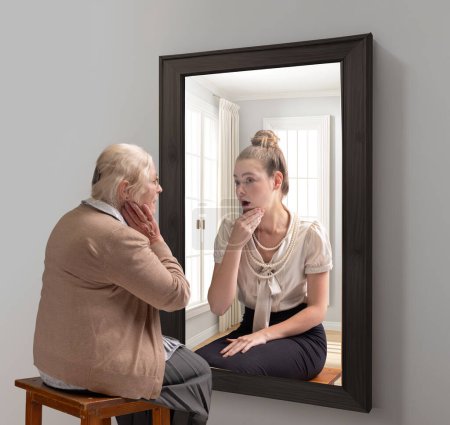 Téléchargez les photos : Collage conceptuel créatif. Femme âgée regardant dans un miroir et se souvenant de son passé. Jeune fille en réflexion. Vieillir. Concept de présent, passé et futur, âge, mode de vie, souvenirs, génération, annonce - en image libre de droit