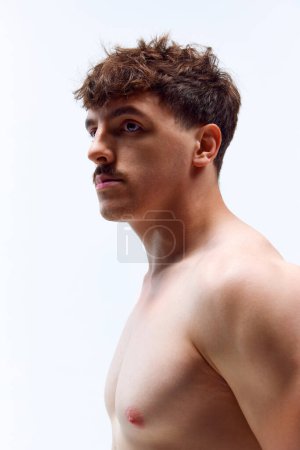 Photo for Portrait of young handsome man posing shirtless with serious facial expression against grey studio background. Muscular body. Concept of mans beauty, sportive and healthy lifestyle, athletic body - Royalty Free Image