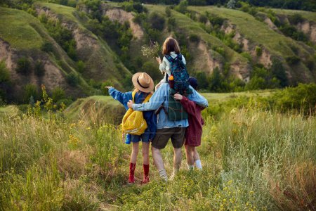Photo for Lovely young parents, man and woman going hiking on beautiful trails, hills. Breathtaking landscape of summer nature. Concept of leisure time, fun, nature, active lifestyle, family, travel - Royalty Free Image