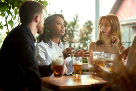 Photo for Friends, co-workers meeting together after work, celebrating projects, spending lovely time together , drinking beer at pub, cafe. Concept of leisure time, business, communication, fun, alcohol drink - Royalty Free Image