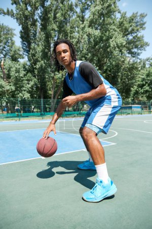 Photo for Dynamic image of young man, basketball player in blue uniform, training outdoors on playground on warm sunny day. Concept of professional sport, competition, hobby, game, active lifestyle - Royalty Free Image