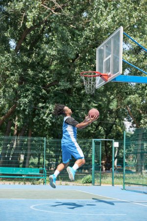 Photo for Dynamic image of young man, basketball player in motion, throwing ball into basket. Outdoors training. Concept of professional sport, competition, hobby, game, active lifestyle - Royalty Free Image