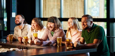 Téléchargez les photos : Des gens joyeux, des amis assis dans le bar, regardant attentivement la traduction du match de football, boire, boire de la bière, s'amuser. Concept de compétition sportive, passe-temps, mode de vie, émotions humaines, plaisir - en image libre de droit
