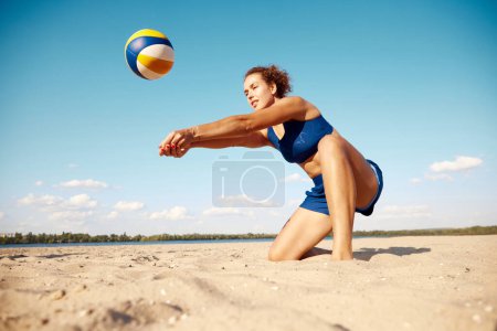Téléchargez les photos : Jeunes femmes athlétiques jouant au beach-volley lors d'une chaude journée d'été en plein air. Frapper la balle avec les mains. Concentration. Concept de sport, mode de vie actif et sain, passe-temps, été, publicité - en image libre de droit
