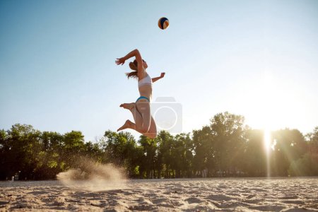 Photo for Young sportive, athletic woman in swimsuit playing beach volleyball outdoors on sand near river. Fresh air and training. Concept of sport, active and healthy lifestyle, hobby, summertime, ad - Royalty Free Image