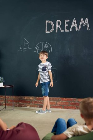 Photo for Little smart child, boy standing at chalkboard and drawing his dreamings. Imagination. Car doodles. Psychology and creative thinking. Concept of school, education, childhood, knowledge, lifestyle - Royalty Free Image