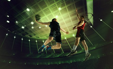 Photo for Dynamic image of young men, professional basketball players in motion, in a jump with ball under basket on 3D arena. Top view. Concept of professional sport, competition, action, hobby, game. - Royalty Free Image