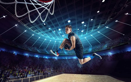 Téléchargez les photos : Slam dunk. Jeune homme, joueur de basket professionnel sur le stade 3D, arène pendant le match, sauter avec la balle. Concept de sport professionnel, compétition, action, passe-temps, jeu, action et mouvement - en image libre de droit