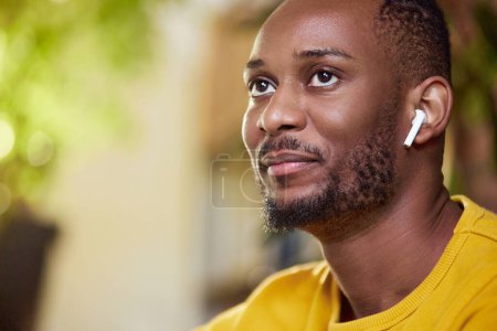 Photo for Close-up portrait of delightful young african man wearing earphones for comfort talk and listening of information. Student, freelancer. Business and education, freelance job, modern lifestyle concept - Royalty Free Image
