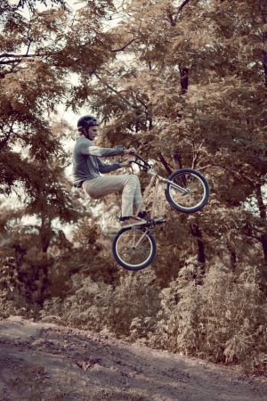 Photo for Young man training riding bmx bike outdoors in park with special roads for extreme riding. Strength and endurance. Concept of active lifestyle, sport, extreme, dynamics, hobby, fitness - Royalty Free Image
