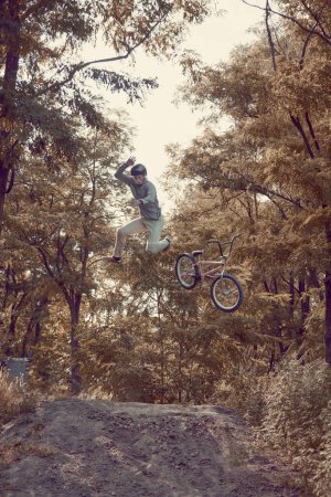 Photo for Young man riding bmx bike outdoors in forest on summer day, training,m doing tricks. Dangerous and difficult activity. Concept of active lifestyle, sport, extreme, dynamics, hobby, freestyle - Royalty Free Image