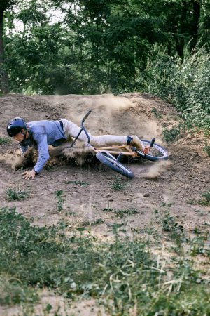 Photo for Young man in helmet riding bmx bike in forest, doing dangerous tricks and falling down. Difficult training before race. Concept of active lifestyle, sport, extreme, dynamics, hobby, freestyle - Royalty Free Image