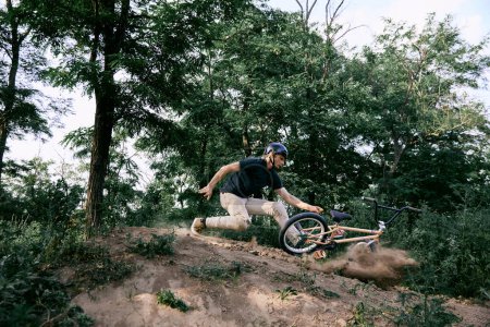 Photo for Young man in helmet riding bmx bike in forest, doing dangerous tricks and falling down. Difficult training before race. Concept of active lifestyle, sport, extreme, dynamics, hobby, freestyle - Royalty Free Image