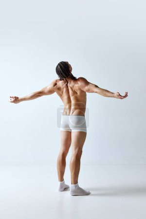 Photo for Rear view image of man posing shirtless in underwear against grey studio background. Relief back, muscular, healthy body. Concept of mens beauty, body care, sport, wellness, healthy lifestyle, ad - Royalty Free Image