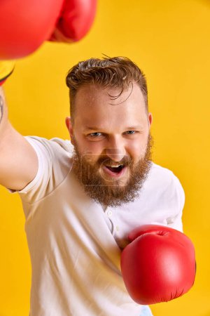 Photo for Bearded emotional man in sportswear and boxing gloves against bright yellow background. Winner, success. Concept of sport, strength, fashion, meme emotions, lifestyle, ad - Royalty Free Image
