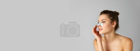 Photo for Beautiful young woman using face, nose mask for cleansing pores against grey studio background. Concept of natural beauty, cosmetology and dermatology, skincare, cosmetics, ad. Banner - Royalty Free Image