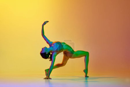 Photo for Talented, flexible young woman dancing contemp in underwear against gradient yellow orange background in neon light. Concept of modern dance style, hobby, art, performance, lifestyle, ad - Royalty Free Image