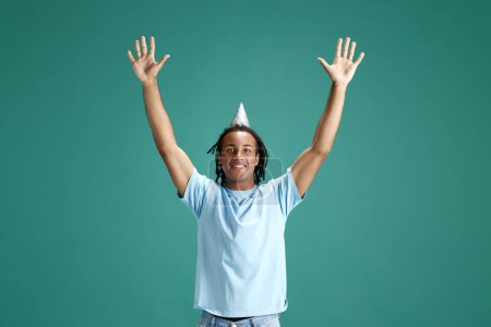 Foto de Hombre joven que usa accesorios para el cabello, celebrando su cumpleaños contra el fondo verde del estudio. Fiesta y diversión. Concepto de juventud, emociones humanas, estilo de vida, moda, expresiones faciales, anuncio - Imagen libre de derechos