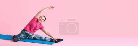 Foto de Mujer madura en entrenamiento de ropa deportiva negra, haciendo estiramiento sobre fondo de estudio rosa. Concepto de deporte, estilo de vida saludable, fitness, cuidado corporal, bienestar. Banner. Copiar espacio para anuncio - Imagen libre de derechos