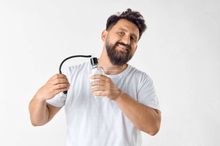 Photo for Bearded smiling man in white t-shirt applying perfume against white studio background. Good smell. Concept of mens beauty, skin care, cosmetology, health and wellness. Copy space for ad - Royalty Free Image