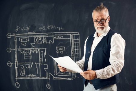 Photo for Stylish senior man, professional architect working with architectural design, making sketches on blackboard. Concept of profession, architecture, creation, occupation, business - Royalty Free Image