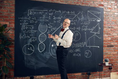 Photo for Young man, scientist, lecturer standing by blackboard with math and scientific formulas, making calculations. Concept of education, science, profession and occupation, knowledge - Royalty Free Image